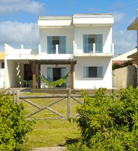 Sobrado beira mar para aluguel diário com grande quintal verde e varandas, acabamento moderno branco