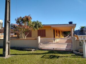 Casa 1 quadra da praia, com muro baixo e acabamento amarelo.