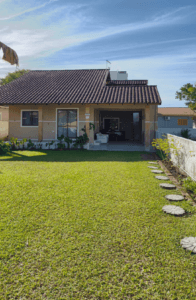 Casa com terraço com gramado verde e garagem com churrasqueira, com acabamento amarelo