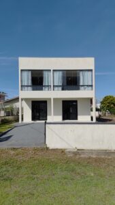 Sobrado para aluguel diário, na quadra da praia, com acabamento moderno branco, 2 portas e 4 janelas