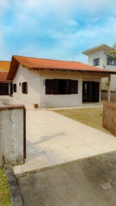 Casa perto da praia com 4 quartos e piscina, com portão de madeira e gramado e céu azul